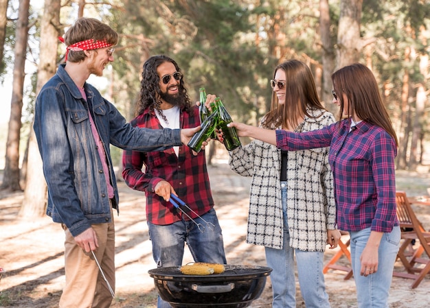 Gruppo di amici che tostano con birra sul barbecue