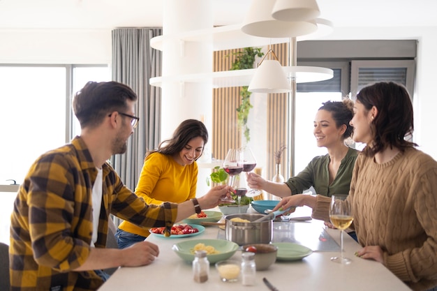 Group of friends toasting with wine in the kitchen