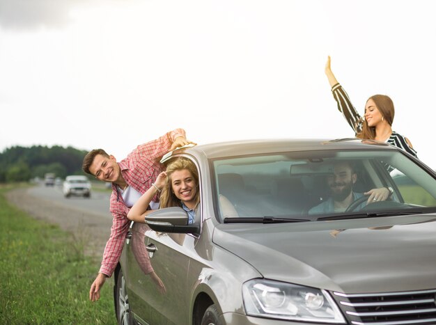 Group of friends travelling in the car hanging out through open window