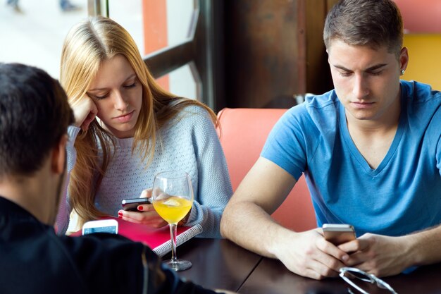Группа друзей, использующих мобильный телефон в кафе.