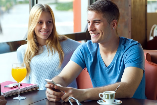 Group of friends using mobile phone in cafe.