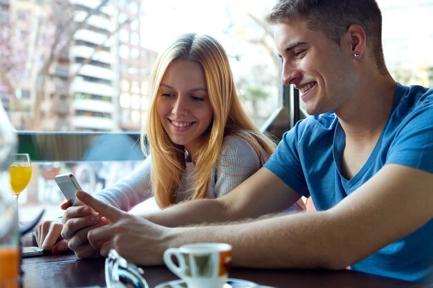 Group of friends using mobile phone in cafe.