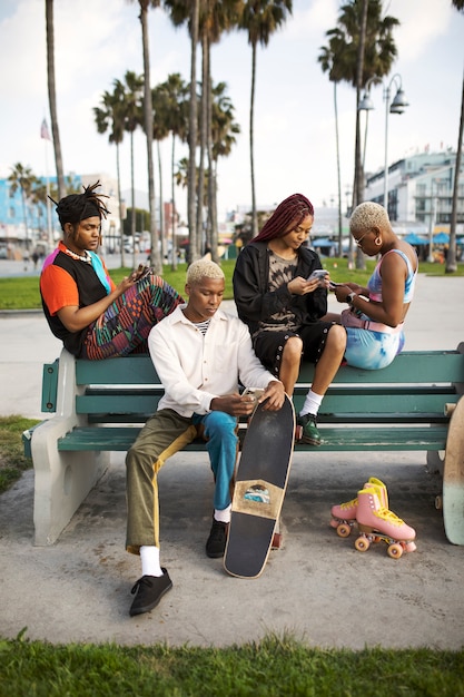 Group of friends using smartphones while sitting on a bench outside in the park