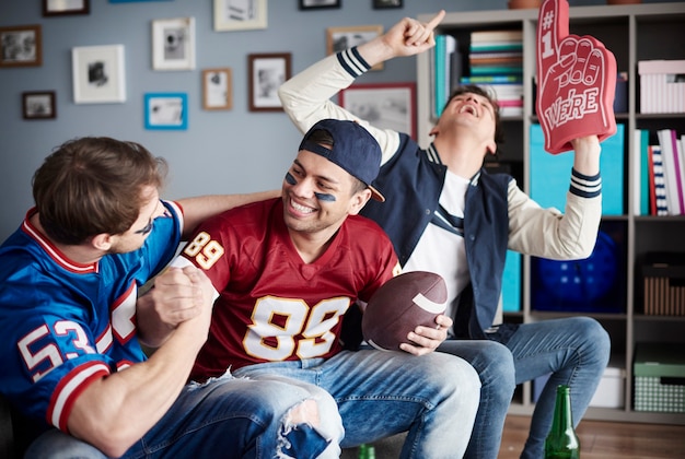 Group of friends watching football at home