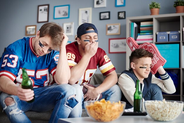 Group of friends watching football at home