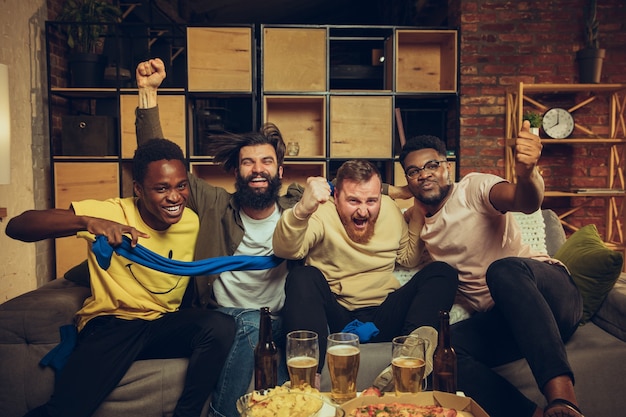 Free photo group of friends watching tv sport match together emotional fans cheering for favourite team watching on exciting game