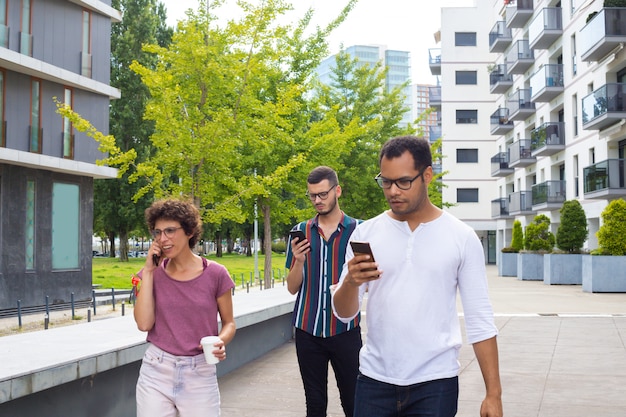 Group of friends with gadgets walking outside