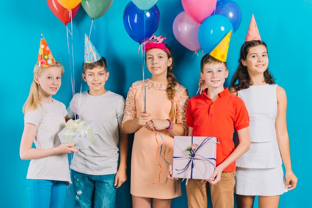 Группа друзей с подарками и красочные воздушные шары на синем фоне