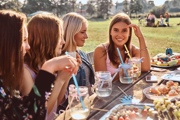 Gruppo di amiche sedute al tavolo insieme per festeggiare un compleanno nel parco all'aperto.