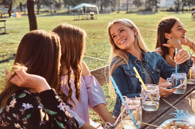 Group of girlfriends sitting at the table together celebrating a birthday at the outdoor park.