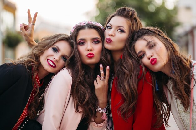 Group of gorgeous girlfriends smiling and gesturing at camera.