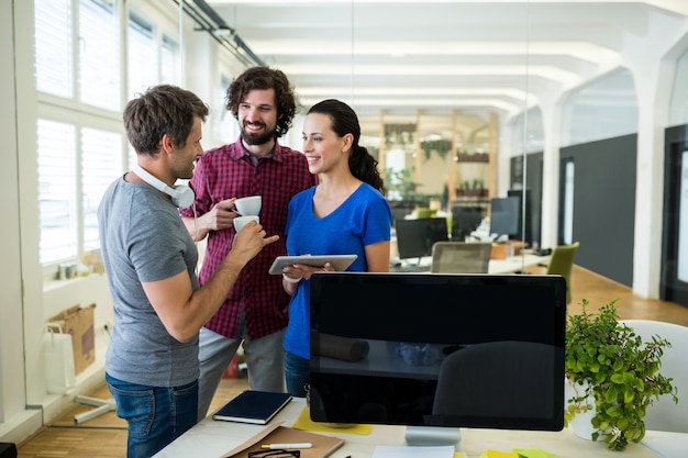 Group of graphics designers using digital tablet while having coffee