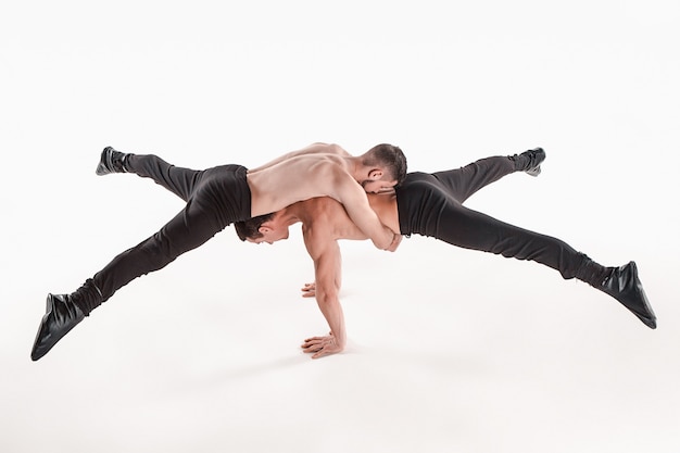 Foto gratuita gruppo di uomini caucasici acrobatici relativi alla ginnastica sulla posa dell'equilibrio