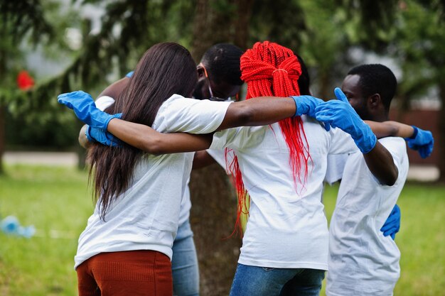 Group of happy african volunteers hugs in park Africa volunteering charity people and ecology concept