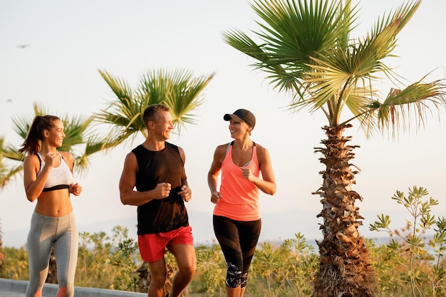 Group of happy athletic people jogging and talking to each other outdoors.