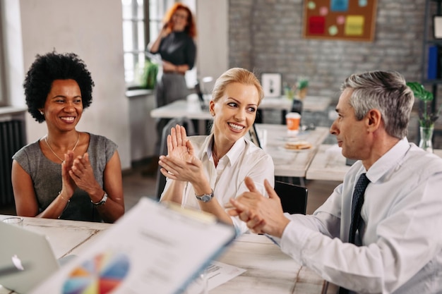 Group of happy business colleagues clapping hands after attending an presentation in the office