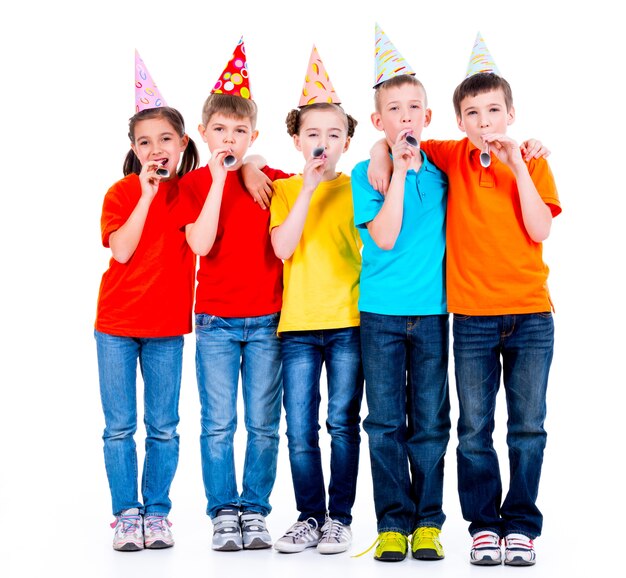 Group of happy children in colored t-shirts with party blowers - isolated on a white background