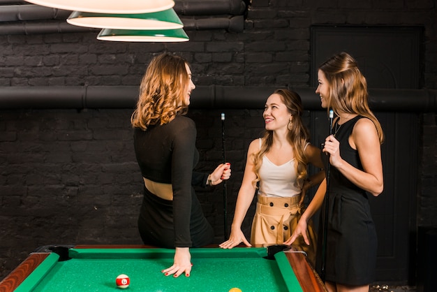 Foto gratuita gruppo di amici femminili felici che stanno vicino alla tavola dello snooker