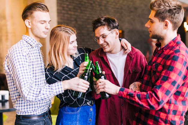 Foto gratuita gruppo di amici felici tintinnanti la bottiglia di birra