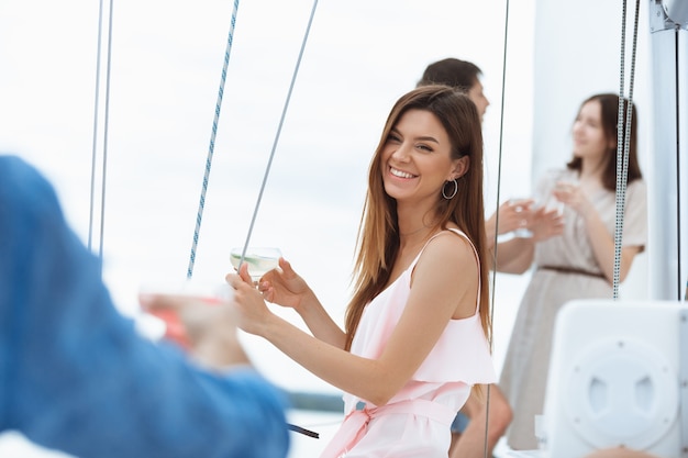 Group of happy friends drinking vodka cocktails at boat party outdoor, summer