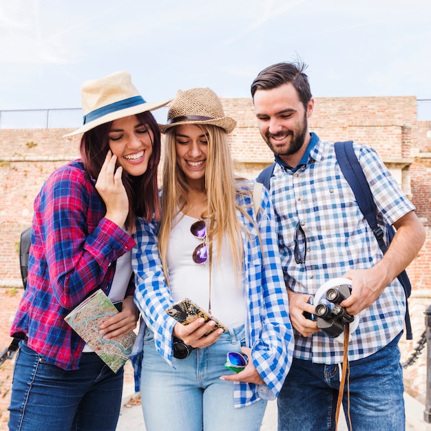 Free photo group of happy friends looking at cellphone