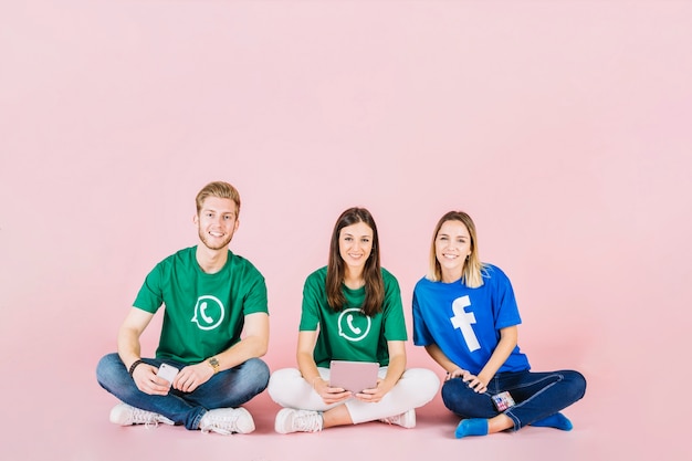 Group of happy friends sitting on pink background