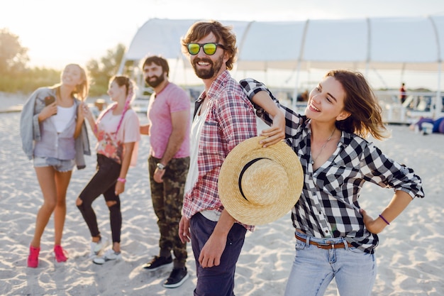 Group of happy friends spending amazing time together and walking along the sunny beach