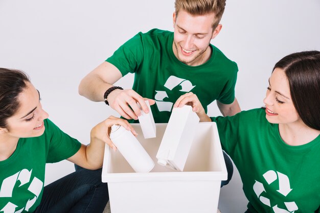 Group of happy friends throwing bottles in white dustbin