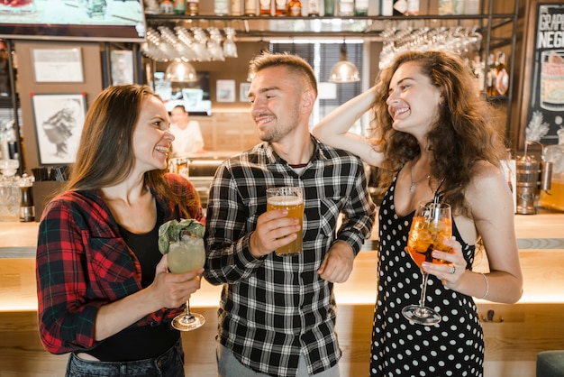 Группа счастливых друзей с напитками в баре
