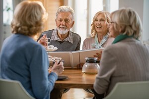 Group of happy mature people talking about their memories while gathering at home focus is on mature couple with photo album