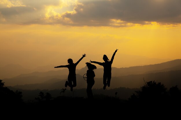 Group of happy people jumping in the mountain at sunset