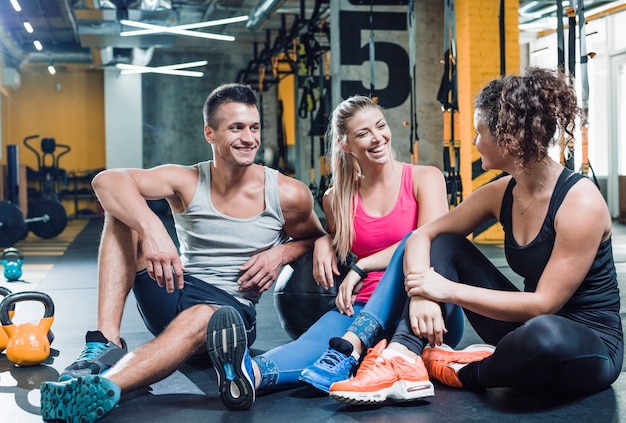 Free photo group of happy people sitting on floor after workout