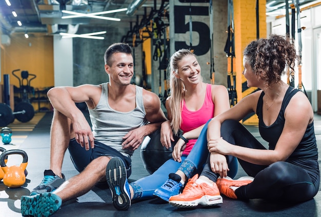 Group of happy people sitting on floor after workout