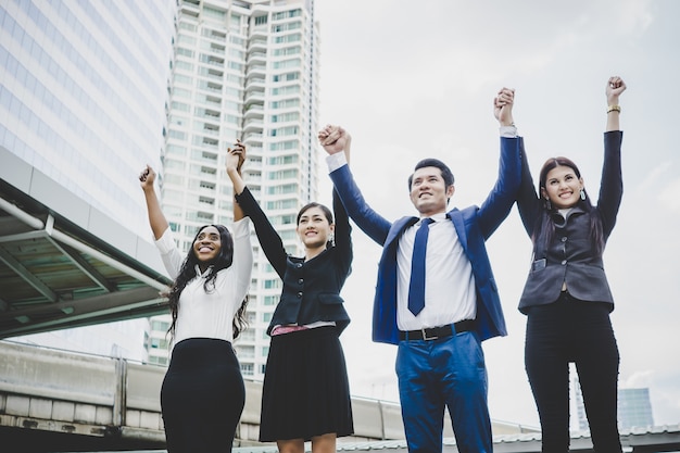 Free photo group of happy young business people with hands in the air success on their plans.