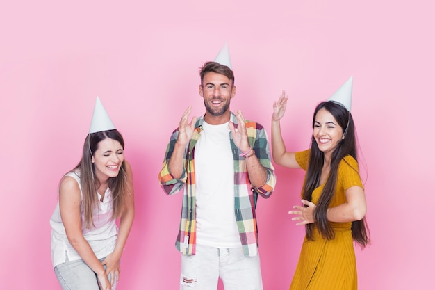 Group of happy young friends having fun on pink background