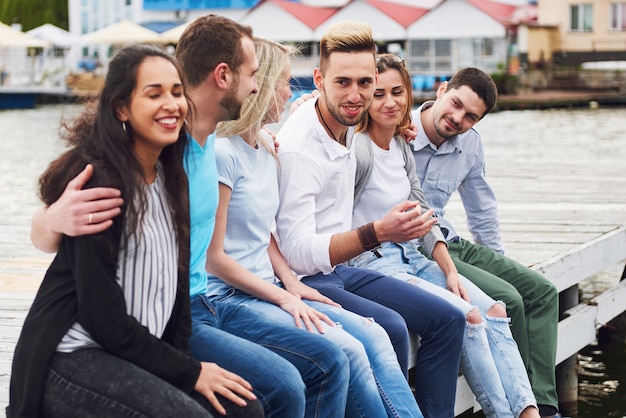 Group of happy young friends on the pier, pleasure in playing creates emotional life.