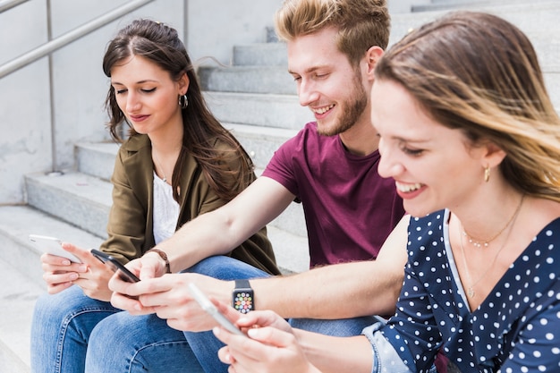 Gruppo di giovani amici felici utilizzando il telefono cellulare