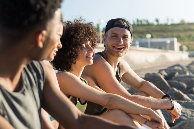 Foto gratuita gruppo di giovani felici in abiti sportivi che parlano mentre riposando