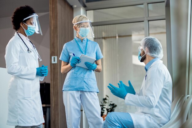 Group of healthcare workers talking ta hospital hallway while working during coronavirus pandemic