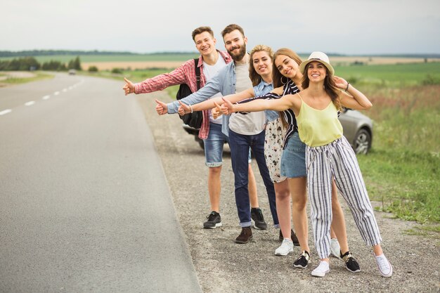 Group of hitchhikers waiting for car on countryside road