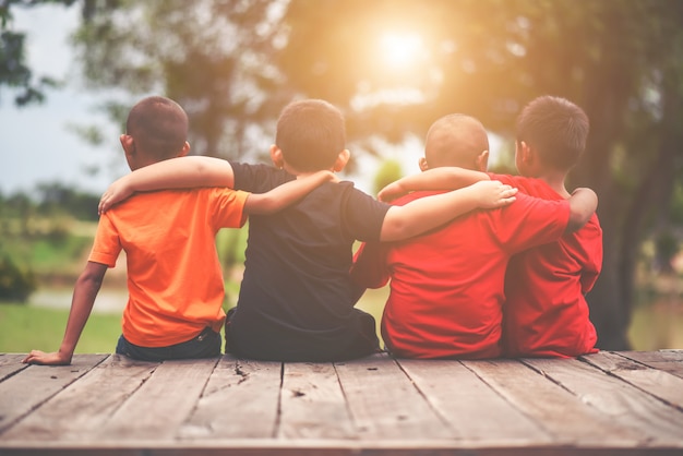 Group of kids friends arm around sitting together Free Photo