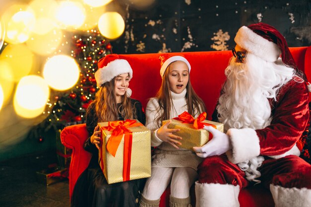 Group of kids sitting with santa and presents on christmas eve