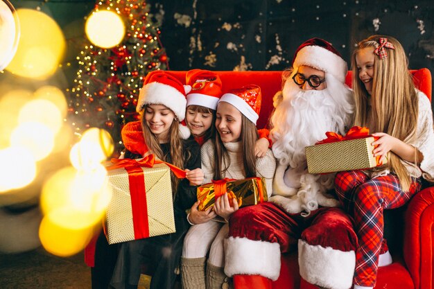 Group of kids sitting with santa and presents on christmas eve