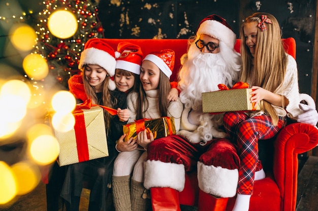 Group of kids sitting with santa and presents on christmas eve