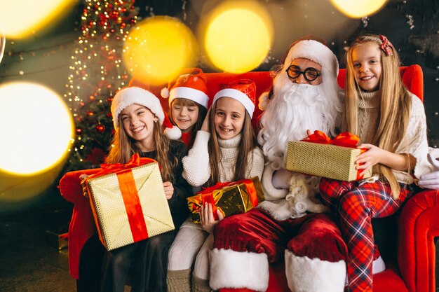 Group of kids sitting with santa and presents on christmas eve