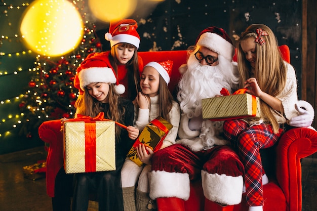 Free photo group of kids sitting with santa and presents on christmas eve