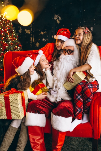 Группа детей, сидя с Санта и подарки в канун Рождества
