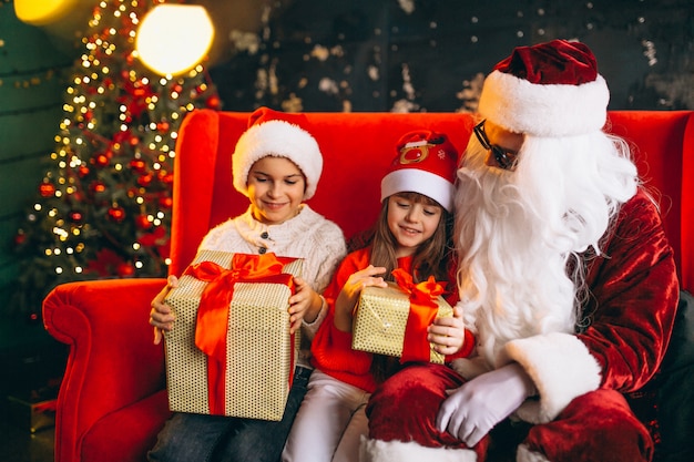 Group of kids sitting with santa and presents on christmas eve