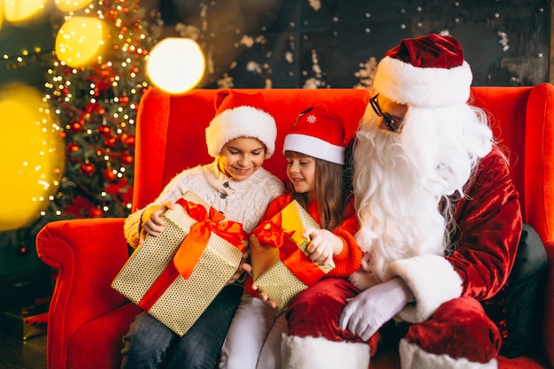 Group of kids sitting with santa and presents on christmas eve