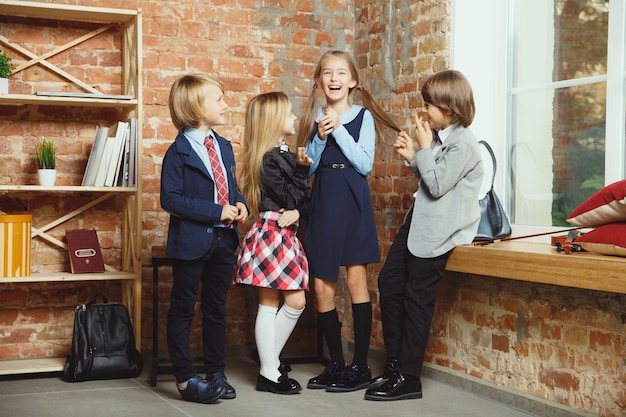 Group of kids spending time after school together. Handsome friends resting after classes before start of doing homework. Modern loft interior. Schooltime, friendship, education, togetherness concept.